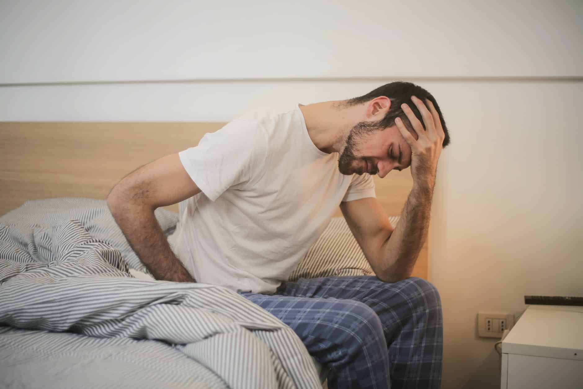 young man in sleepwear suffering from headache in morning